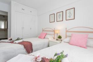 2 camas en un dormitorio con color rosa y blanco en Vistahermosa Piscinas vista Bahía, en El Puerto de Santa María