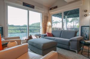 een woonkamer met een bank, stoelen en ramen bij Chiberta - entre plages et golf in Anglet