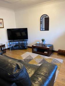 a living room with a leather couch and a flat screen tv at Black Bull Barn in Kirkby Stephen