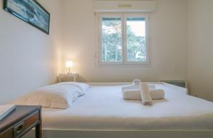 een wit bed in een kamer met een raam bij Chiberta - entre plages et golf in Anglet