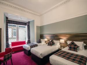a hotel room with two beds and a red chair at Argyll Western Hotel in Glasgow