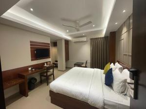 een slaapkamer met een bed, een bureau en een televisie bij Five Elements in Visakhapatnam