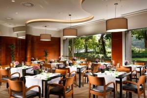 a restaurant with white tables and chairs and a large window at UNAHOTELS Cusani Milano in Milan