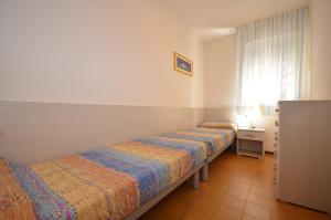 two beds sitting in a room with a window at Appartamenti Erica in Bibione