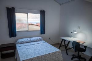 a bedroom with a bed and a desk and a window at Suítes em Casa Duplex no Pontal in Ilhéus