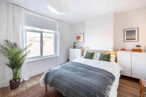 een witte slaapkamer met een bed en een raam bij Relax in Stunning House in Great Central Location in Cardiff
