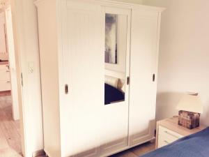 einen weißen Schrank mit einer Tür in einem Schlafzimmer in der Unterkunft Reetkate Kaltenhoern in Tetenbüll