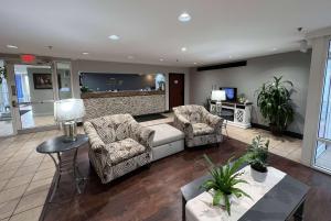sala de estar con 2 sillas y sofá en Baymont by Wyndham Peoria en Peoria