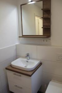 La salle de bains est pourvue d'un lavabo et d'un miroir. dans l'établissement LA2 Galerie - Ferienreihenhaus LA2, à Schottwarden