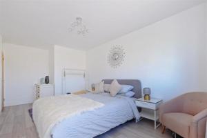 a white bedroom with a bed and a chair at Stunning family home, walking distance to Herne Bay Beach! in Kent