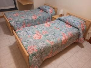 a bedroom with two beds with a floral bedspread at Le Torri Apartments in Perugia