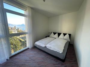 Apartment Residenza Canto Sereno by Interhome في Minusio: غرفة نوم بسرير ونافذة كبيرة