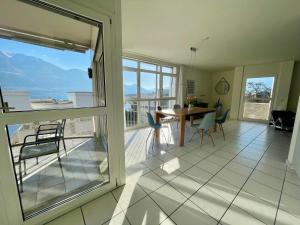 ein Wohnzimmer mit einem Tisch und Stühlen sowie einem Balkon in der Unterkunft Apartment Residenza Canto Sereno by Interhome in Minusio