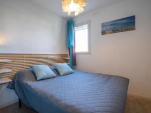 a bedroom with a bed with blue pillows and a window at Apartment Les Caraïbes-1 by Interhome in Le Grau-du-Roi