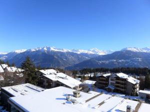 a city with snow covered roofs and mountains in the background at Apartment Jeanne D'Arc Apt- H-58 by Interhome in Crans-Montana