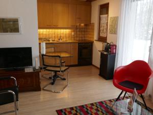 eine Küche mit einem roten Stuhl, einem Tisch und einem TV in der Unterkunft Apartment Chalet Sunneblick by Interhome in Grindelwald