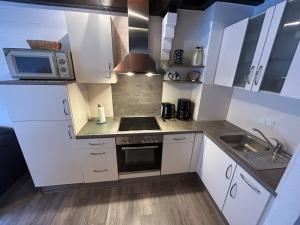 een keuken met witte kasten, een wastafel en een magnetron bij Holiday Home Müter by Interhome in Norddeich