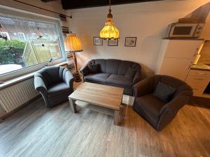 een woonkamer met een bank, stoelen en een tafel bij Holiday Home Müter by Interhome in Norddeich