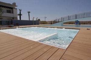 una gran piscina con suelo de madera y una terraza de madera en Comfy apartment in a quiet area en Bibione