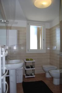 ein Bad mit 2 Waschbecken, einem WC und einem Fenster in der Unterkunft Comfy apartment in a quiet area in Bibione