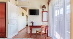 a room with a table with a chair and a television at Rigas Hotel Skopelos in Skopelos Town