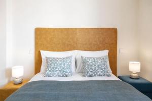 uma cama com almofadas azuis e brancas e 2 candeeiros em Nazaré Boutique Apartment II na Nazaré