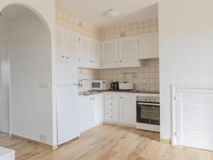 una cocina blanca con armarios y electrodomésticos blancos en Apartment Son Bou Gardens Apt 2 dorm by Interhome, en Son Bou