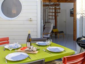 a green table with plates of food and a bottle of wine at Holiday Home Ker Penthièvre by Interhome in Penthièvre
