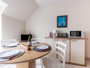 a dining room with a wooden table and white chairs at Apartment Le Petit Robinson-3 by Interhome in La Richardais