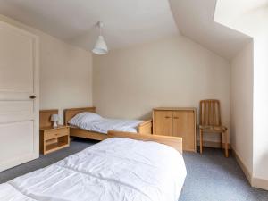 een slaapkamer met 2 bedden en een stoel bij Apartment Le Petit Robinson-3 by Interhome in La Richardais