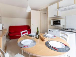 een keuken met een houten tafel met borden en wijnglazen bij Apartment Le Petit Robinson-3 by Interhome in La Richardais