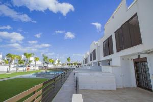 un bâtiment blanc avec une clôture à côté d'une cour dans l'établissement 240 Lux Pool Home -Alicante Holiday, à Torre de la Horadada