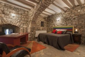 sypialnia z łóżkiem i biurkiem w kamiennej ścianie w obiekcie Castell de Fonolleres w mieście Fonolleres