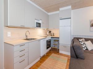 uma cozinha com armários brancos e um sofá em Holiday Home Loma-koli 3 by Interhome em Hattusaari