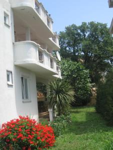 a white building with red flowers in front of it at Apartments Mond in Sutomore