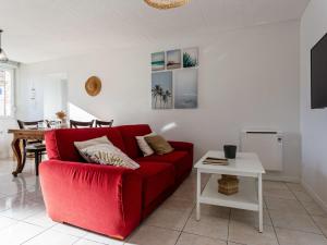 eine rote Couch in einem Wohnzimmer mit einem Tisch in der Unterkunft Holiday Home Les Chardons by Interhome in Pirou