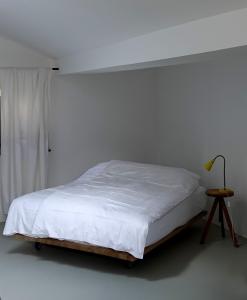 a white bedroom with a bed and a table at Bretzenstudios in Hall in Tirol