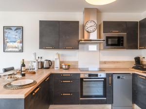 een keuken met bruine kasten en een klok aan de muur bij Holiday Home Palot 7 by Interhome in Mimizan