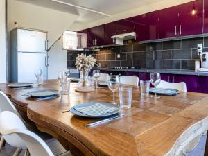 a large wooden table in a kitchen with purple cabinets at Holiday Home Le Coquelicot by Interhome in Pirou +14 photos