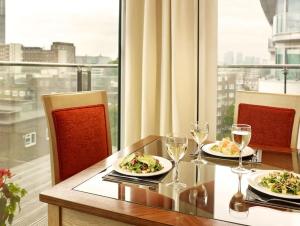 - une table avec deux assiettes de nourriture et des verres à vin dans l'établissement Marlin Apartments London Bridge - Empire Square, à Londres