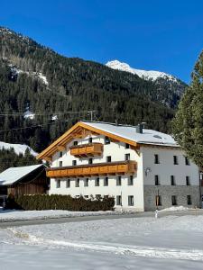 ein großes weißes Gebäude vor einem Berg in der Unterkunft APART Kirschner in Sankt Leonhard im Pitztal