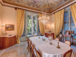 una sala da pranzo con tavolo, sedie e lampadario pendente di Villa Platamone a Como
