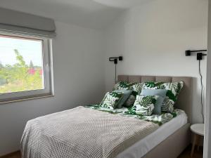 a bed with green and white pillows and a window at Boya Home in Wilkasy