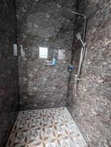 a bathroom with a shower in a stone wall at Bright Peaceful Villa in Kerobokan