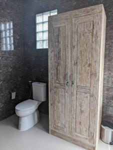 a bathroom with a toilet and a wooden door at Bright Peaceful Villa in Kerobokan