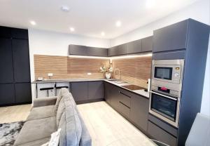 a kitchen with black cabinets and a couch in a room at Stylish Flat in Bournemouth Town Centre in Bournemouth