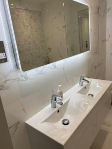 a white bathroom with a sink and a mirror at Stylish Flat in Bournemouth Town Centre in Bournemouth