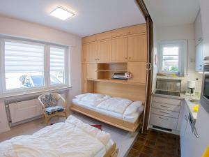 a bedroom with two beds and a desk and a kitchen at Ferienwohnung Emilia, FeWo Vermittlung Nordsee in Dangast +3 photos