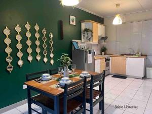 eine Küche mit einem Holztisch mit Stühlen und einer grünen Wand in der Unterkunft THE GREEN @SELESA HILLHOMES BUKIT TINGGI BENTONG in Bentong