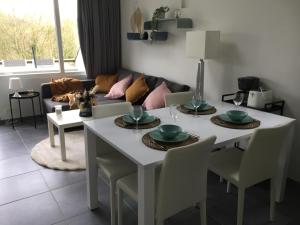 un salon avec une table et des chaises blanches dans l'établissement Les terrasses de Malmedy duplex 420, à Malmedy